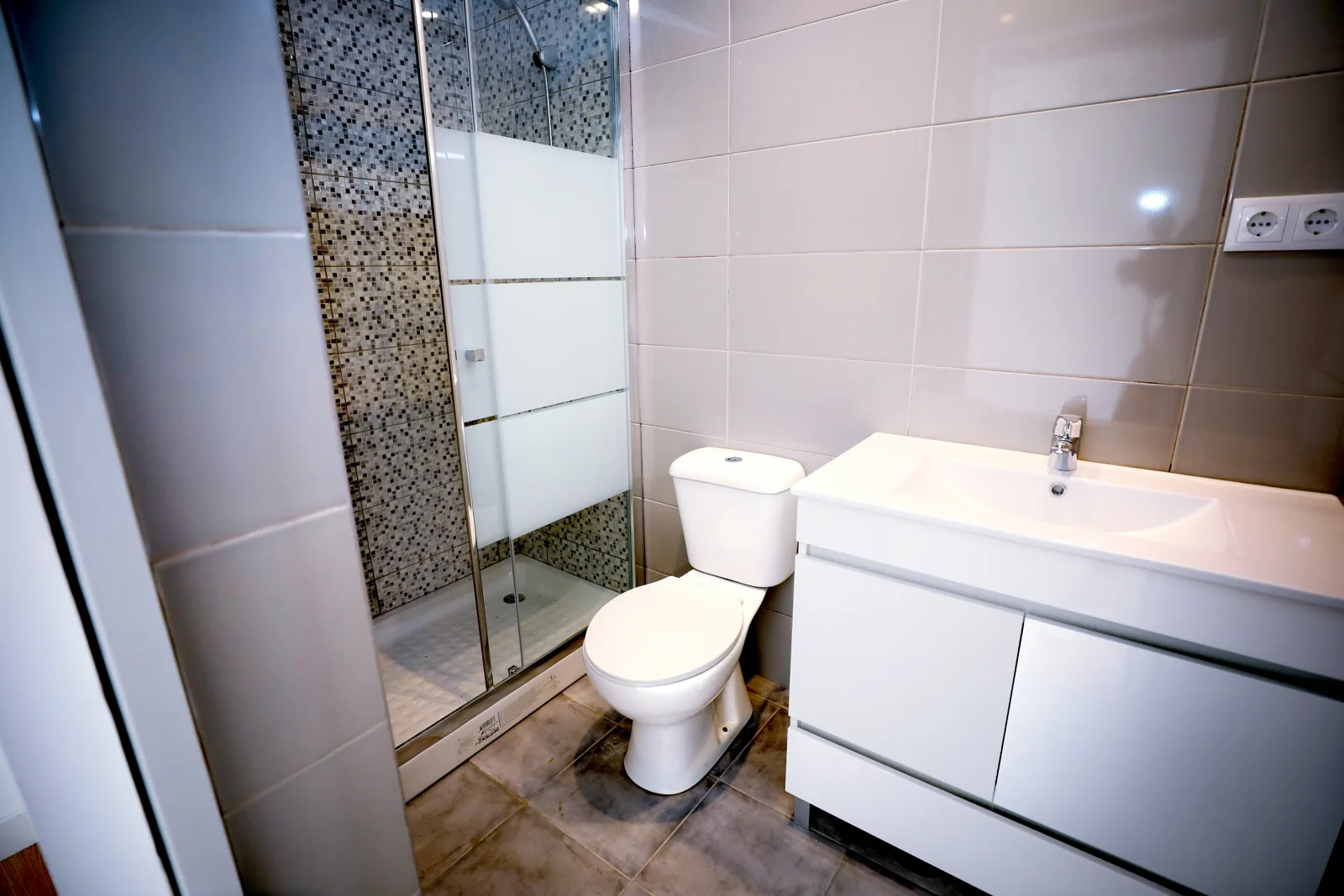 Casa de banho renovada com duche, revestimentos e móvel com lavatório